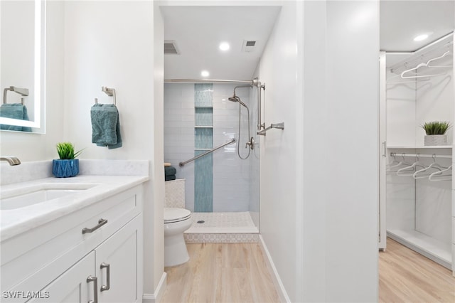 bathroom with vanity, toilet, wood-type flooring, and tiled shower