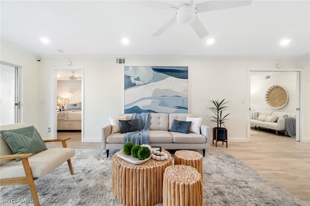 living room with ceiling fan, crown molding, and light hardwood / wood-style flooring