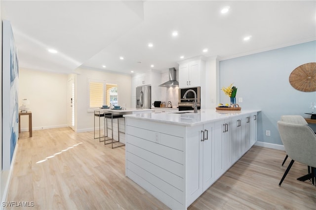 kitchen with white cabinets, sink, wall chimney exhaust hood, stainless steel fridge, and kitchen peninsula