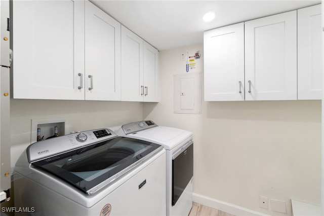 laundry area featuring cabinets, independent washer and dryer, electric panel, and light hardwood / wood-style flooring