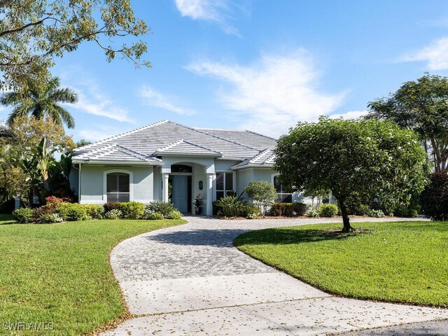 565 Coral Dr, Naples, FL 34102 - single story home featuring stucco siding, curved driveway, a front lawn, and a tiled roof