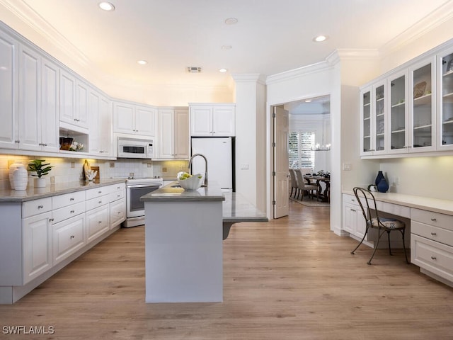 kitchen with white appliances, light hardwood / wood-style flooring, white cabinetry, and a kitchen island with sink