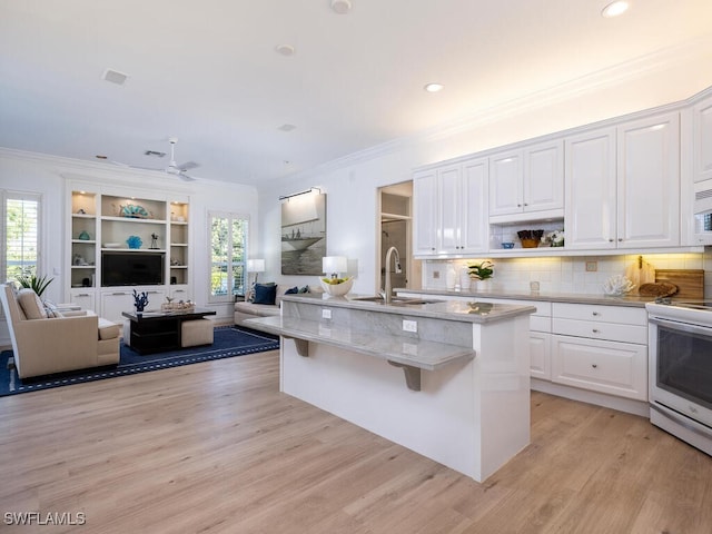 kitchen featuring sink, white appliances, a kitchen island with sink, white cabinets, and light wood-type flooring