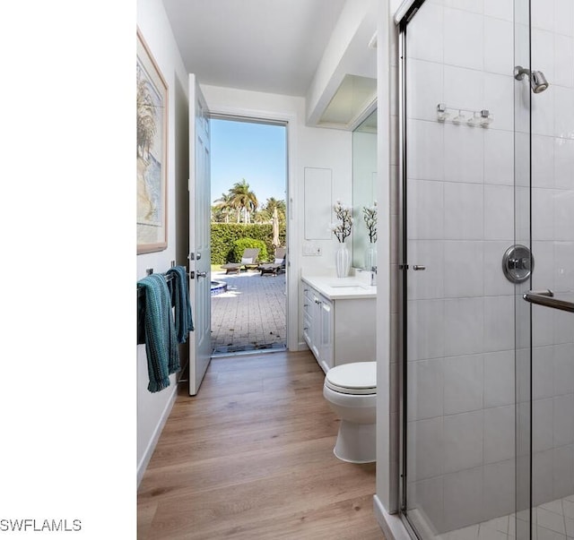 bathroom with wood-type flooring, vanity, toilet, and a shower with shower door