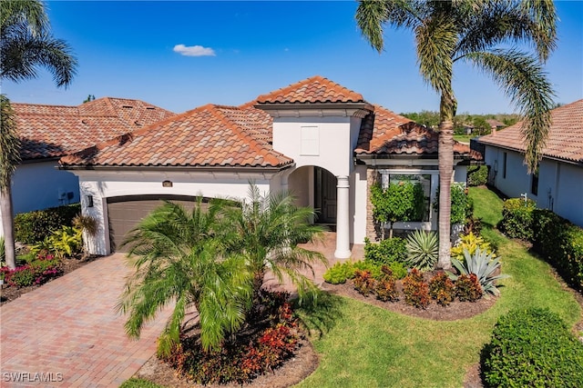 mediterranean / spanish house with a garage and a front lawn