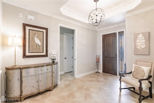 entrance foyer with a chandelier, a tray ceiling, and crown molding