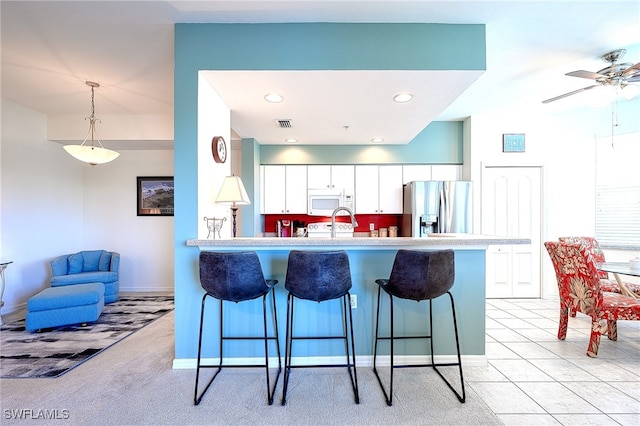 kitchen featuring white cabinetry, stainless steel refrigerator with ice dispenser, light colored carpet, pendant lighting, and a breakfast bar area