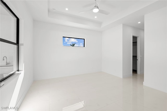 spare room featuring a raised ceiling and ceiling fan