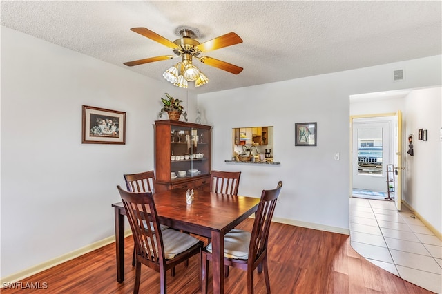 dining room with hardwood / wood-style floors, ceiling fan, and a textured ceiling