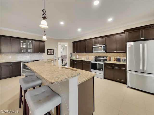 kitchen featuring a kitchen breakfast bar, dark brown cabinets, beverage cooler, and stainless steel appliances