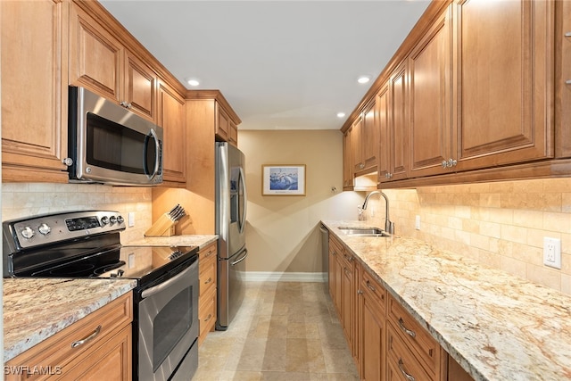 kitchen featuring light stone counters, sink, stainless steel appliances, and tasteful backsplash