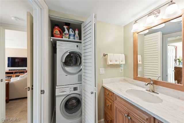 laundry room with crown molding, stacked washer and dryer, and sink