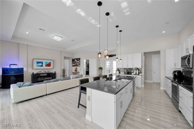 kitchen featuring white cabinetry, sink, a kitchen bar, a center island with sink, and appliances with stainless steel finishes