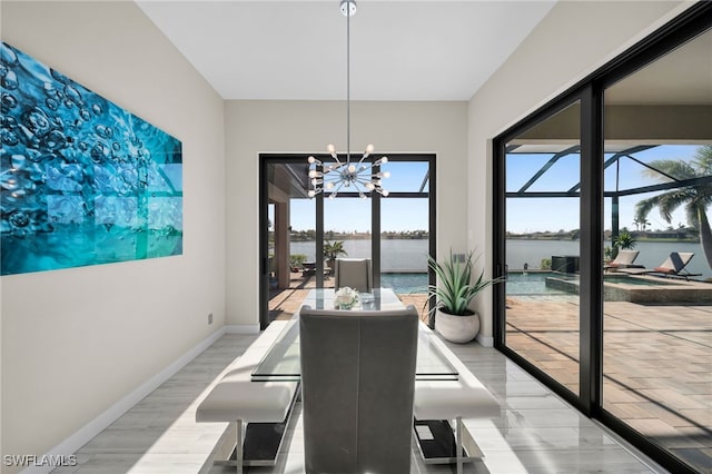 dining space with a water view, light hardwood / wood-style floors, and an inviting chandelier