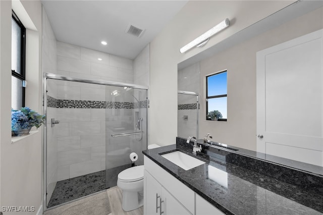 bathroom featuring vanity, an enclosed shower, and toilet