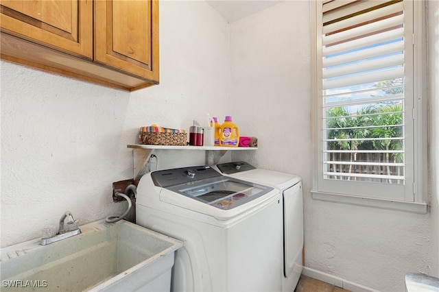 clothes washing area with separate washer and dryer, sink, and cabinets