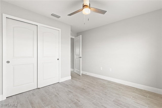 unfurnished bedroom featuring ceiling fan, a closet, and light wood-type flooring