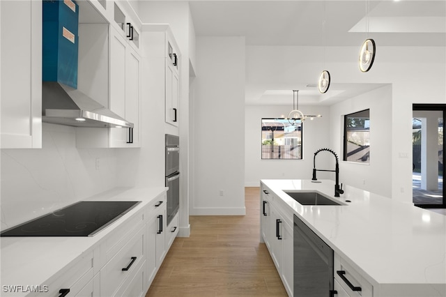 kitchen with tasteful backsplash, an island with sink, stainless steel appliances, wall chimney range hood, and a sink