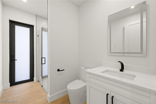 full bathroom featuring toilet, wood finished floors, vanity, baseboards, and a shower stall