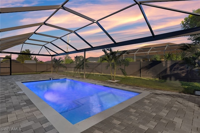 view of pool with glass enclosure, a fenced backyard, and a patio