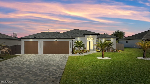 view of front facade featuring an attached garage, fence, decorative driveway, stucco siding, and a front yard