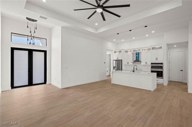 unfurnished living room with baseboards, visible vents, french doors, light wood-type flooring, and a sink