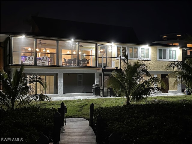 back house at twilight featuring a lawn and a balcony