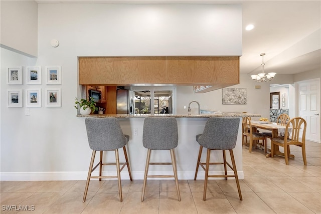 kitchen featuring stainless steel appliances, an inviting chandelier, kitchen peninsula, pendant lighting, and light tile patterned floors