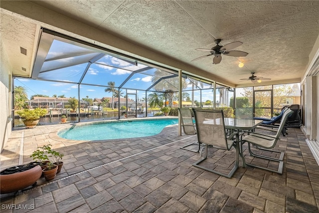 view of swimming pool featuring a lanai, ceiling fan, a water view, and a patio