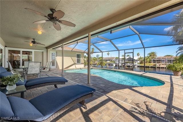 view of pool featuring a patio, a water view, ceiling fan, and a lanai