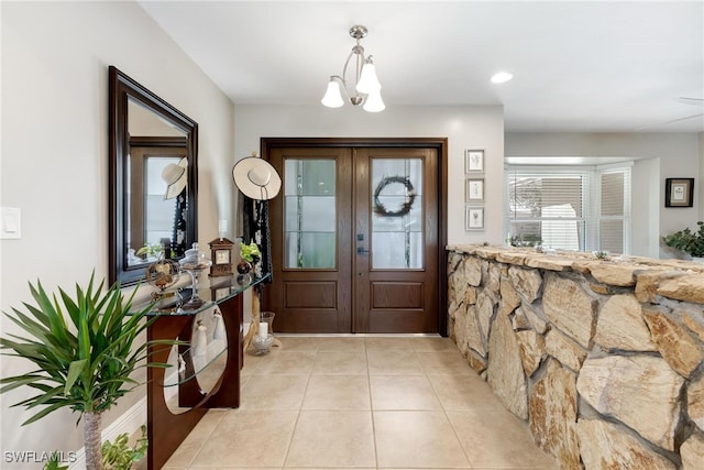 foyer entrance featuring french doors, light tile patterned floors, and a notable chandelier