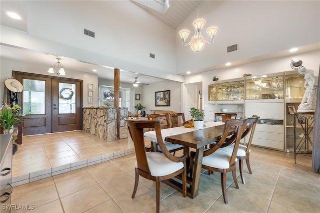 tiled dining space featuring french doors, ceiling fan with notable chandelier, and high vaulted ceiling