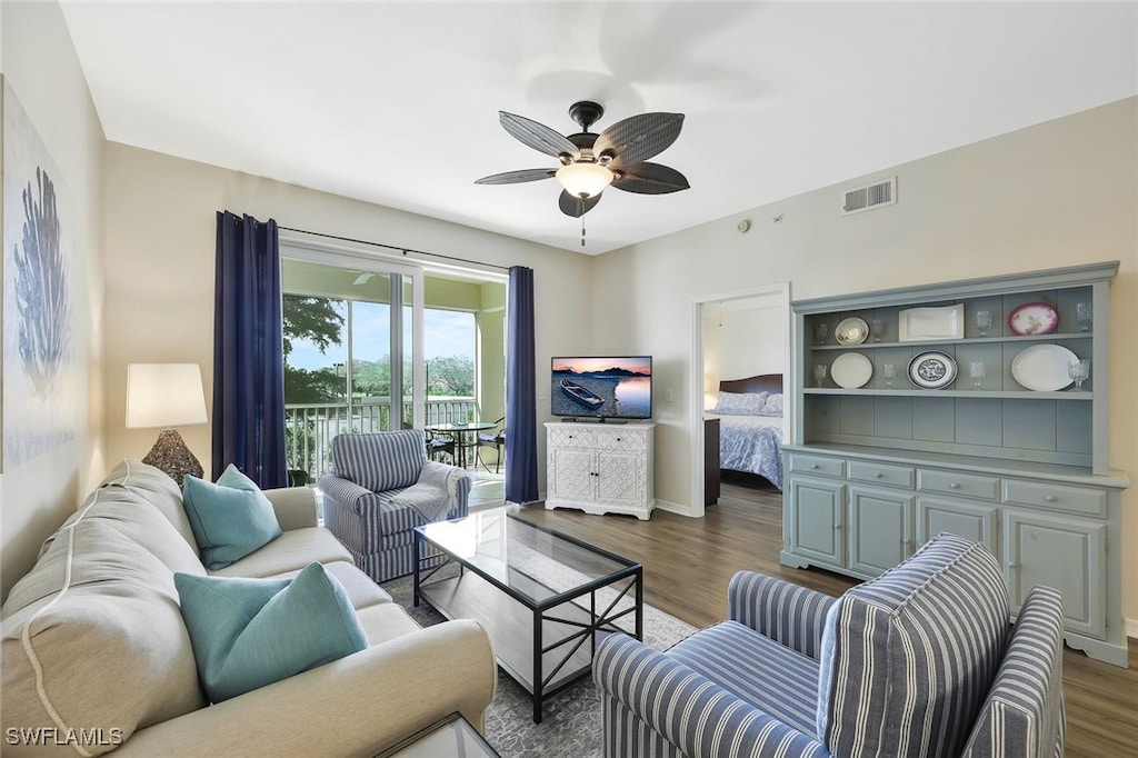 living area featuring baseboards, dark wood-type flooring, visible vents, and a ceiling fan