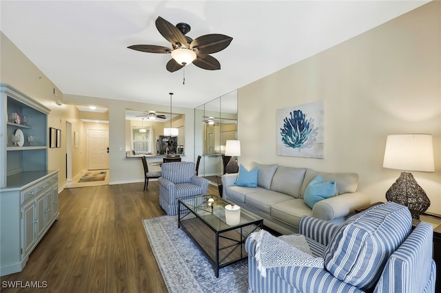 living room with baseboards, dark wood finished floors, and a ceiling fan