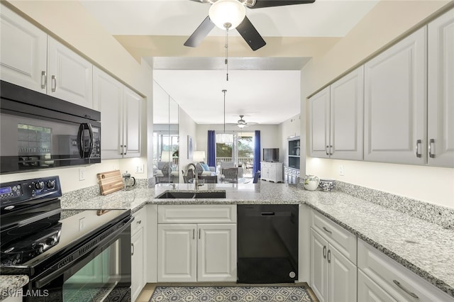 kitchen with a peninsula, black appliances, white cabinets, and a sink