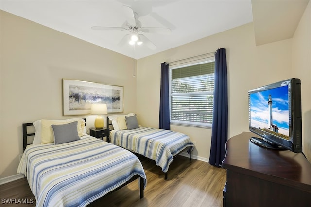 bedroom with ceiling fan, baseboards, and wood finished floors