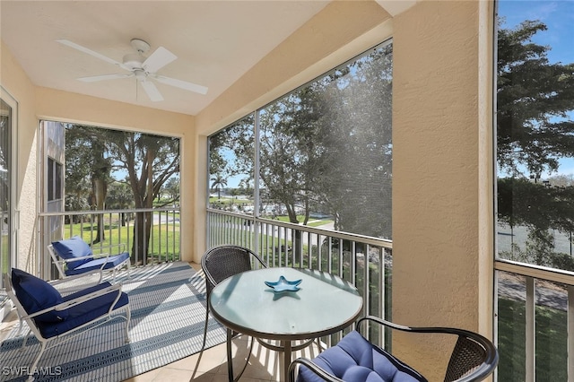 sunroom / solarium with ceiling fan and a water view