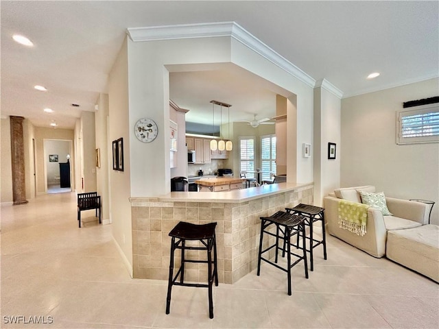 kitchen featuring hanging light fixtures, crown molding, a kitchen breakfast bar, and kitchen peninsula