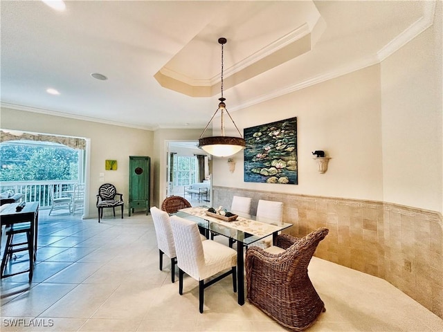 tiled dining area with crown molding, a healthy amount of sunlight, tile walls, and a tray ceiling