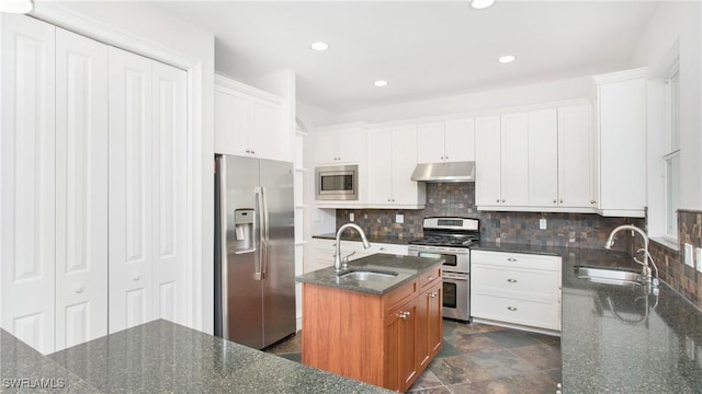 kitchen with white cabinets, appliances with stainless steel finishes, sink, and an island with sink