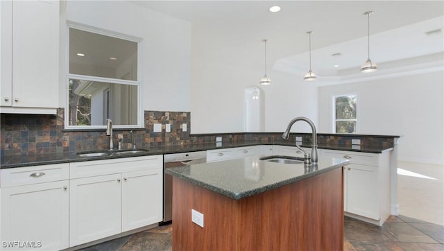 kitchen featuring a kitchen island with sink, sink, and hanging light fixtures