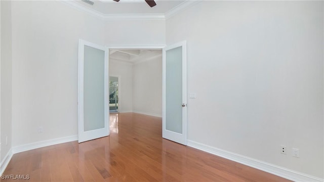 empty room with french doors, ceiling fan, crown molding, and wood-type flooring