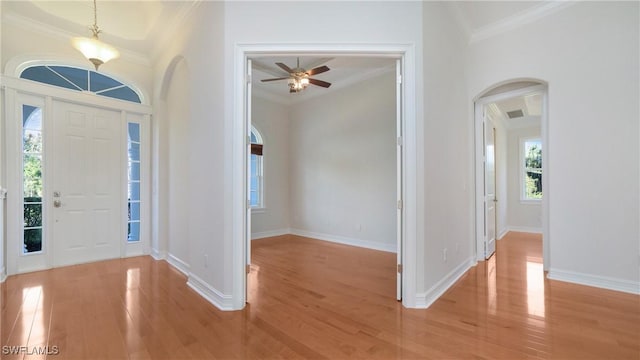 foyer entrance with ceiling fan, ornamental molding, and light wood-type flooring