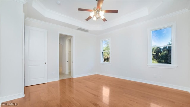 interior space with a raised ceiling, ceiling fan, ornamental molding, and light wood-type flooring