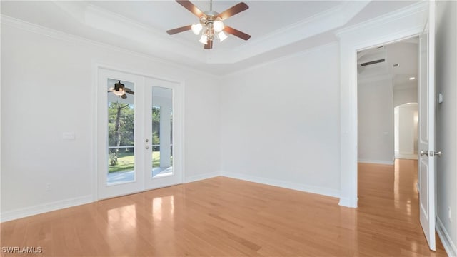 spare room with ceiling fan, french doors, a raised ceiling, crown molding, and light wood-type flooring