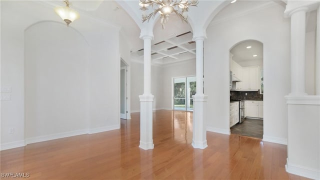 empty room with coffered ceiling, light hardwood / wood-style floors, beamed ceiling, and a chandelier