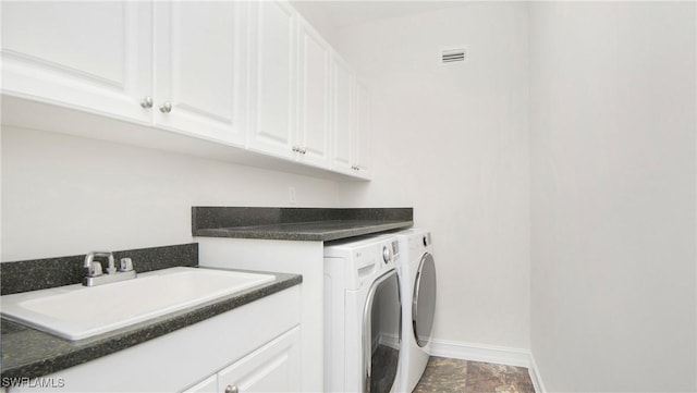 washroom with cabinets, independent washer and dryer, and sink