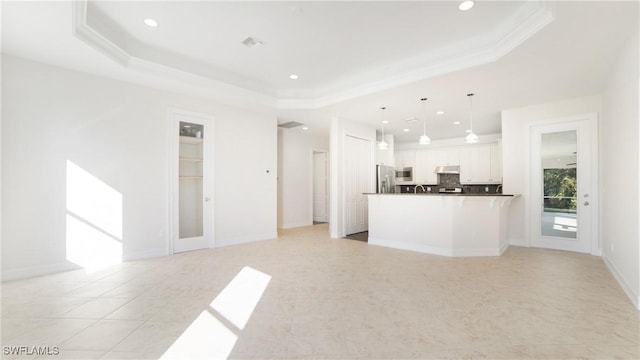 kitchen with white cabinets, appliances with stainless steel finishes, a tray ceiling, and hanging light fixtures