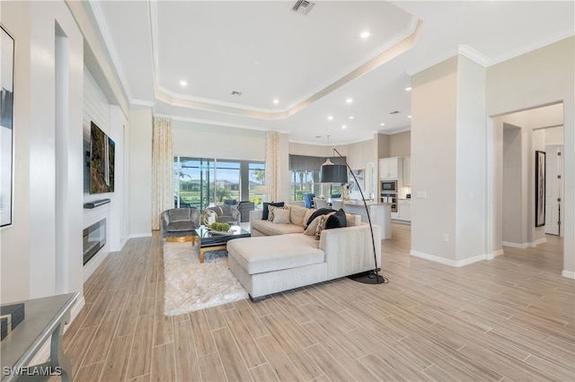 living room featuring a tray ceiling, light hardwood / wood-style floors, and ornamental molding