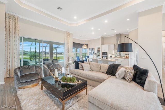 living room featuring a tray ceiling, crown molding, and light hardwood / wood-style floors